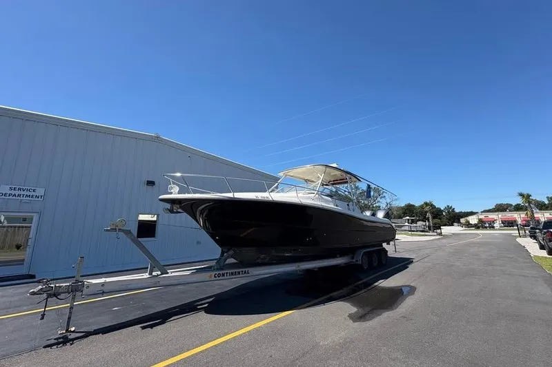 The Image of 2007 Triton 351 Express boat on trailer near service department under clear blue sky. - 1