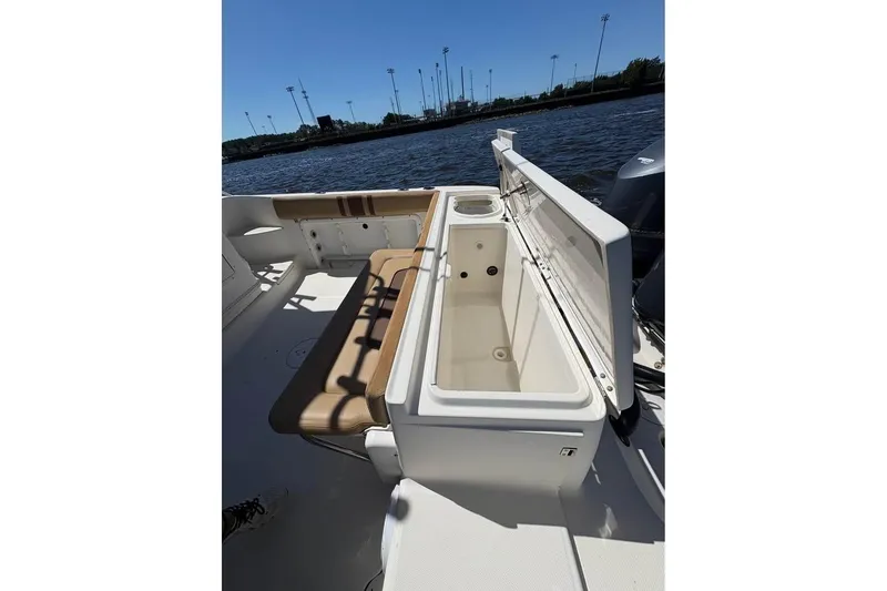 Slide: The Image of 2007 Triton 351 Express boat interior with open storage compartment and seating, near water. - 16