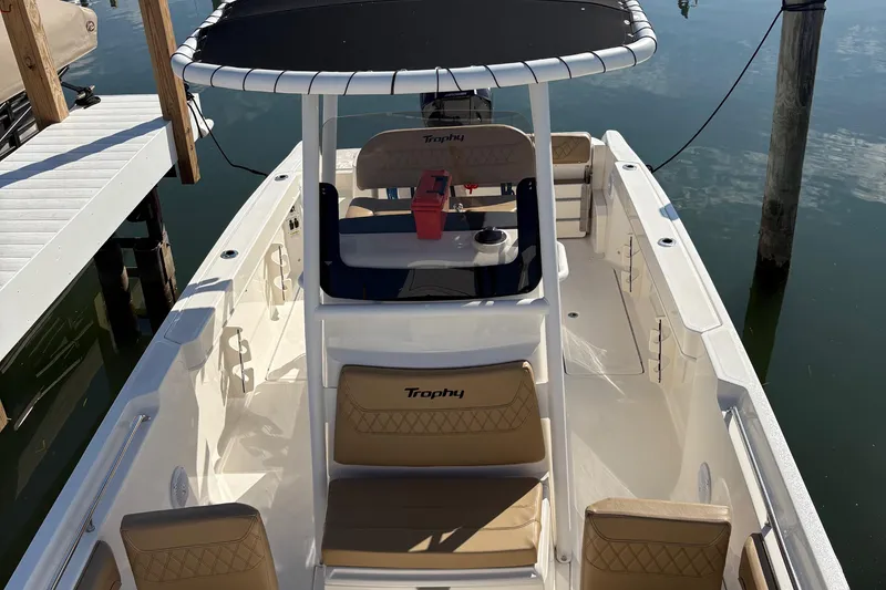 Slide: The Image of 2025 Trophy T22CC boat with tan seating and T-top, docked on calm water. - 1