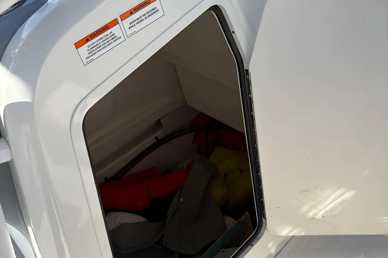 Slide: The Image of Open storage compartment on 2025 Trophy T22CC boat with safety warnings visible. - 7