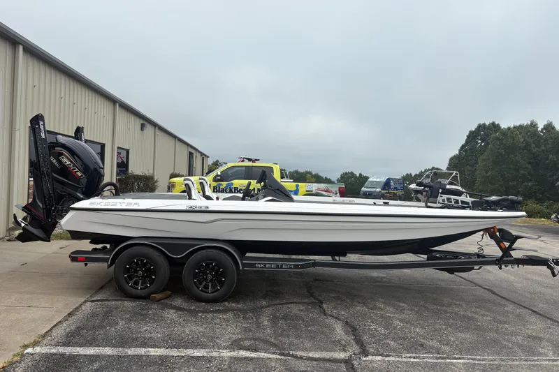 The Image of 2026 Skeeter ZXE21 boat on trailer, parked outdoors near industrial building. - 0
