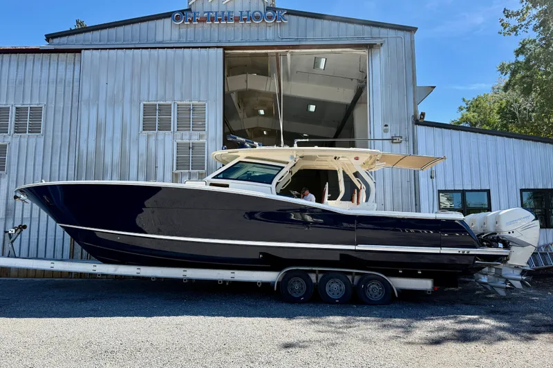 The Image of 2019 Scout 420 LXF boat on calm water under a blue sky. - 0