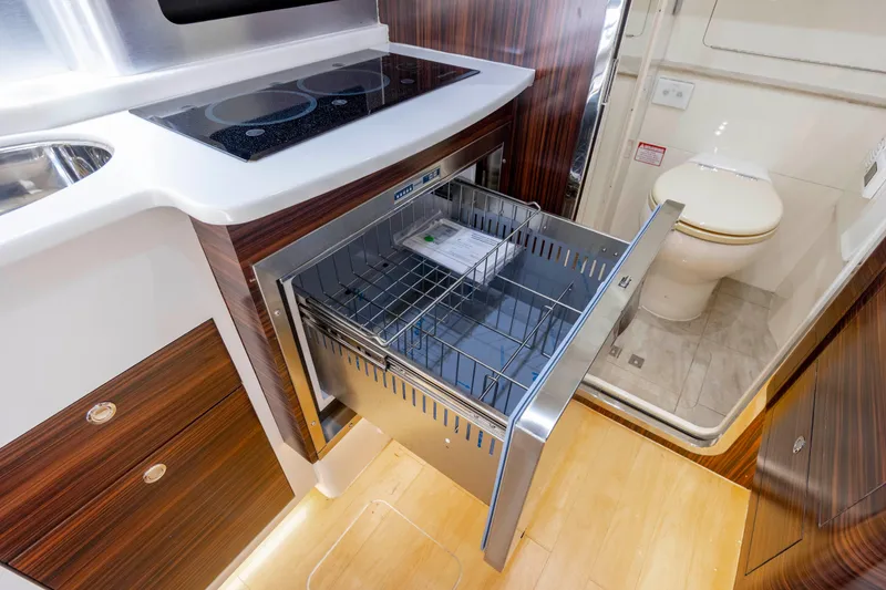 Slide: The Image of 2019 Scout 420 LXF boat on water near a bridge, under a clear blue sky. - 15