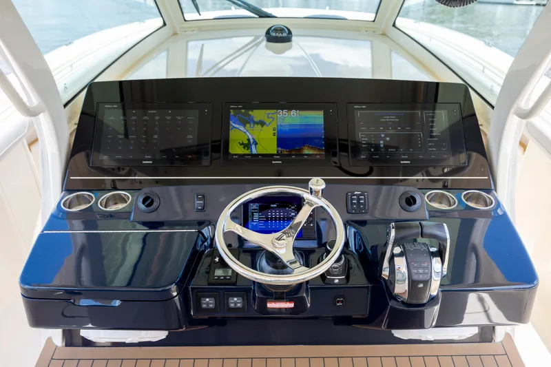 Slide: The Image of 2019 Scout 420 LXF boat interior with luxurious seating, under a clear blue sky near a bridge. - 35