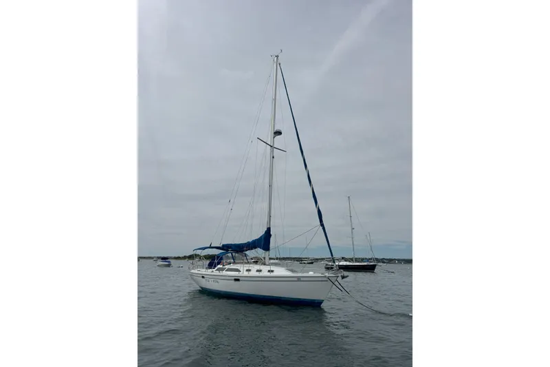 Slide: The Image of 1999 Catalina 34 MkII sailboat anchored on calm water under cloudy sky. - 1