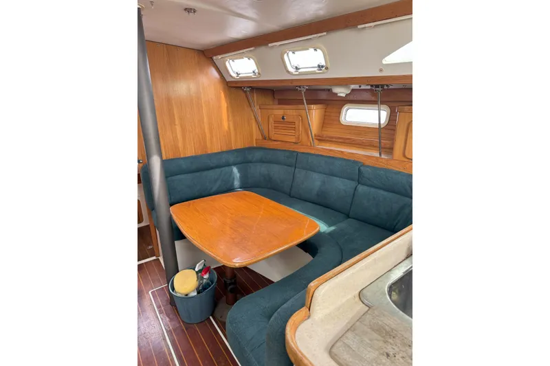 Slide: The Image of 1999 Catalina 34 MkII yacht interior with wooden table and blue cushioned seating. - 10