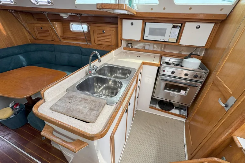 Slide: The Image of 1999 Catalina 34 MkII yacht interior with kitchen, sink, stove, and dining area. - 12