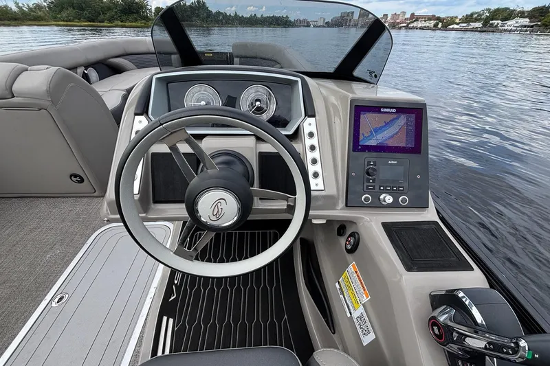 Slide: The Image of 2023 Barletta Corsa 25U boat dashboard with steering wheel and navigation system on a lake. - 7