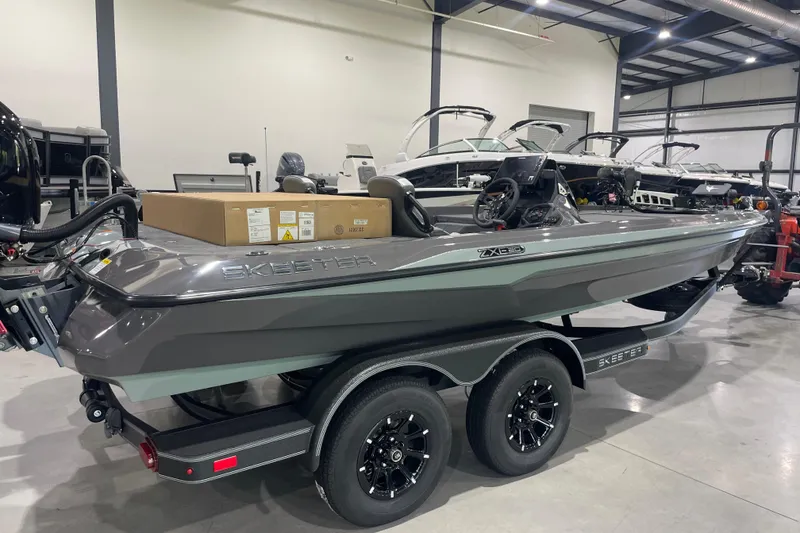Slide: The Image of 2026 Skeeter ZXE20 boat in showroom, sleek design, dual-axle trailer. - 9