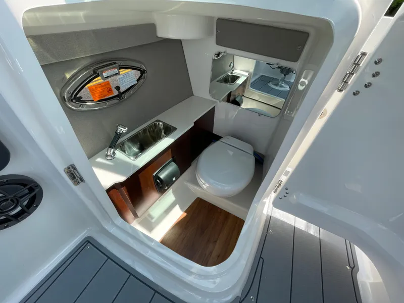 Slide: The Image of 2024 Chaparral 250 OSX boat interior bathroom with sink, toilet, and mirror. - 30