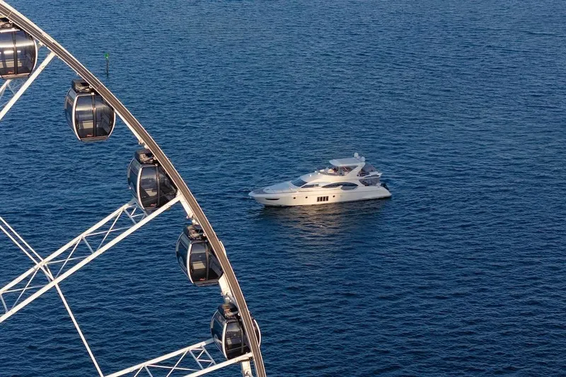 Slide: The Image of Luxurious 2012 Azimut Evolution yacht cruising near a Ferris wheel on the ocean. - 9