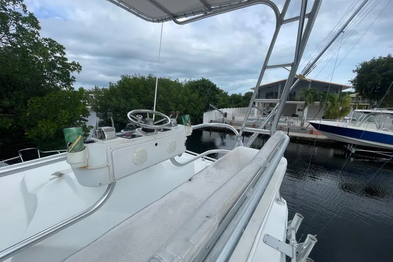Slide: The Image of 1994 Luhrs 32 Open boat helm with steering wheel and controls, docked near waterfront homes. - 5