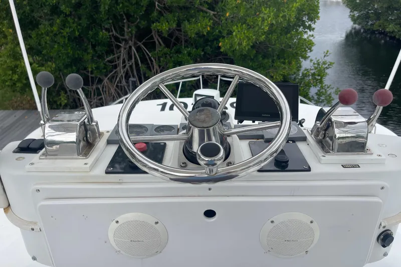 Slide: The Image of 1994 Luhrs 32 Open boat helm with steering wheel and controls, surrounded by lush greenery. - 6