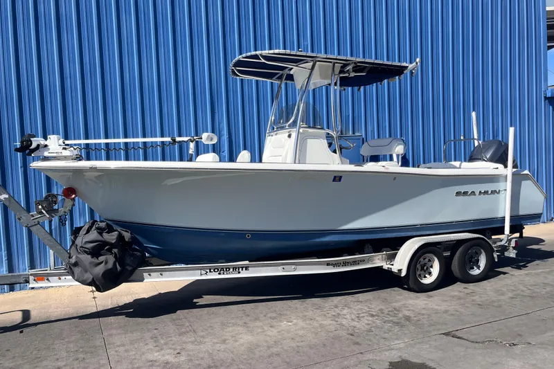 Slide: The Image of 2015 Sea Hunt Ultra 234 boat on trailer, parked by blue wall. - 1