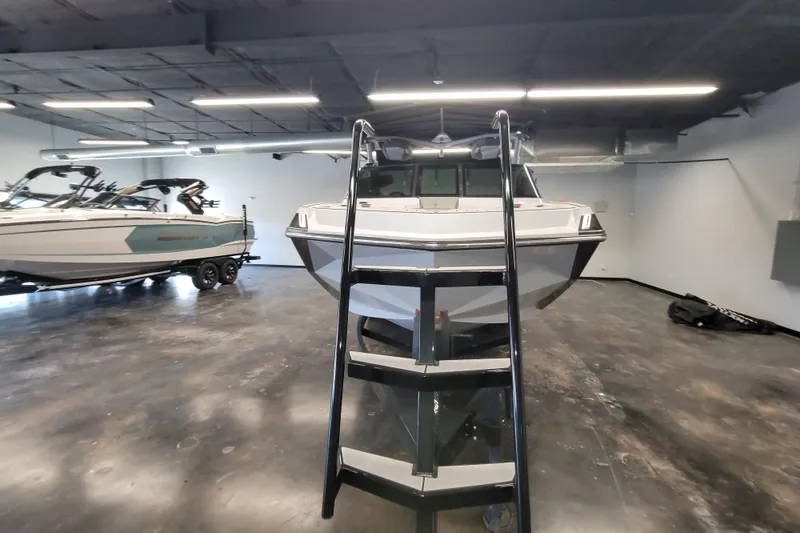 Slide: The Image of 2022 Nautique Super Air Nautique G25 boat in showroom with ladder access. - 21