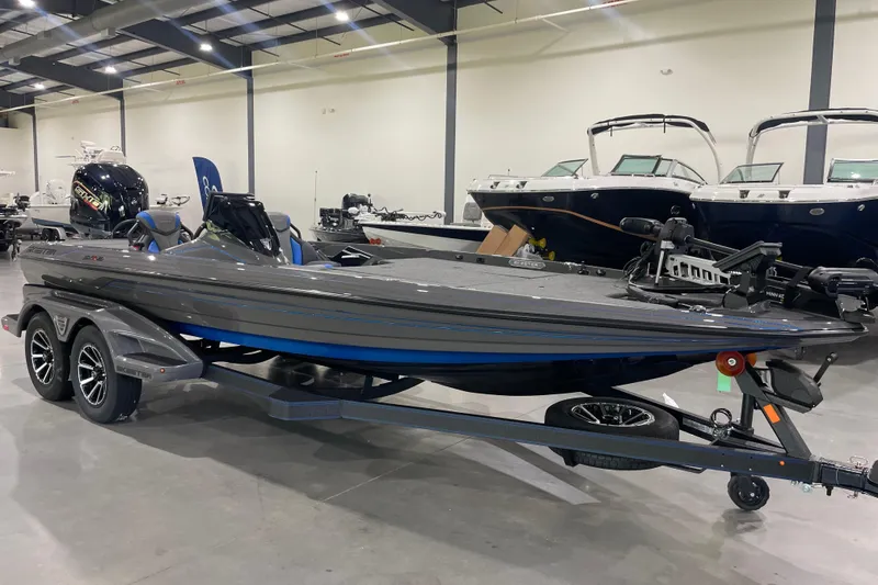 The Image of 2026 Skeeter FXR21 Apex bass boat in showroom, featuring sleek design and dual-axle trailer. - 0