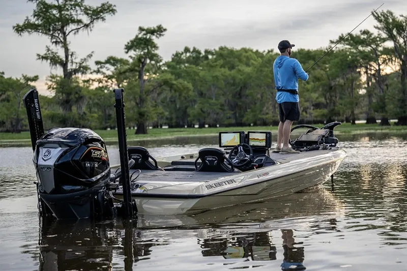 Slide: The Image of Manufacturer Provided Image: 2026 Skeeter FXR21 Apex boat on a serene lake with a person fishing. - 16