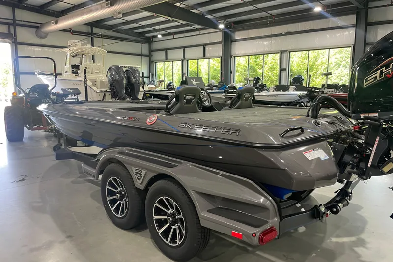 Slide: The Image of 2026 Skeeter FXR21 Apex boat in showroom, sleek design, dual axle trailer. - 8