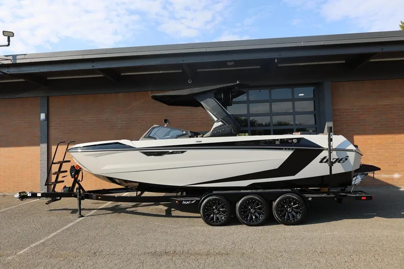 The Image of 2026 Tigé Ultré 25ZX boat on trailer, sleek design, parked outdoors. - 1