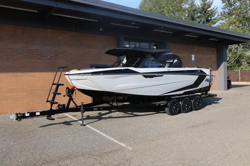 Slide: The Image of 2026 Tigé Ultré 25ZX boat on trailer, parked outdoors near a brick building. - 4