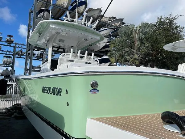 Slide: The Image of 2021 Regulator 34 Center Console boat in mint green, docked with palm trees in background. - 25