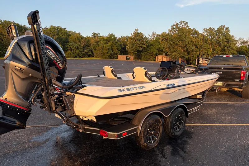 Slide: The Image of 2026 Skeeter ZXE20 boat on trailer, parked in a lot, with trees in background. - 2