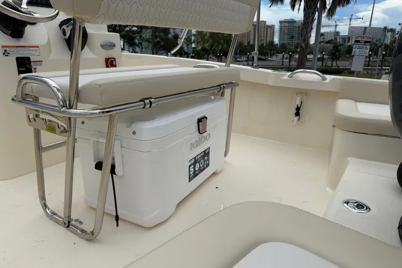 Slide: The Image of 2026 Scout 188 Sportfish boat interior with seating and cooler, docked near cityscape. - 18