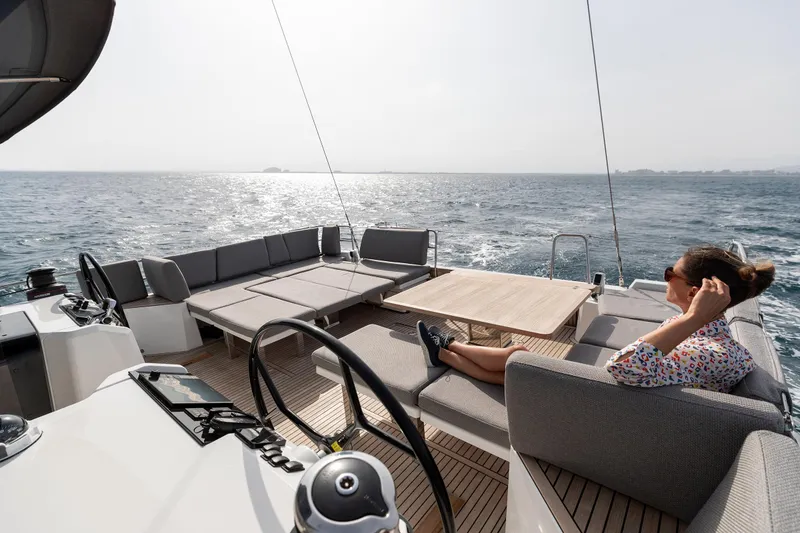 Slide: The Image of 2026 Jeanneau Yachts 55 sailing on open sea with a relaxed passenger on deck. - 11