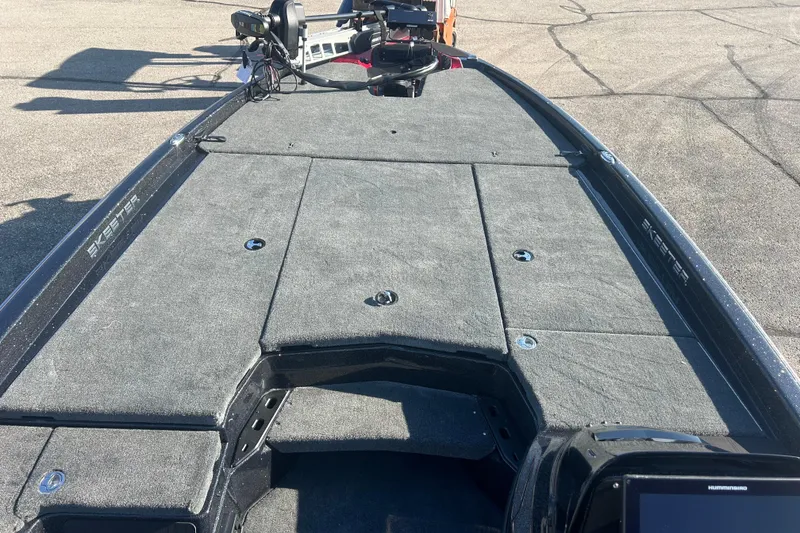 Slide: The Image of 2025 Skeeter ZXR21 boat deck with carpeted surface and fishing equipment. - 16