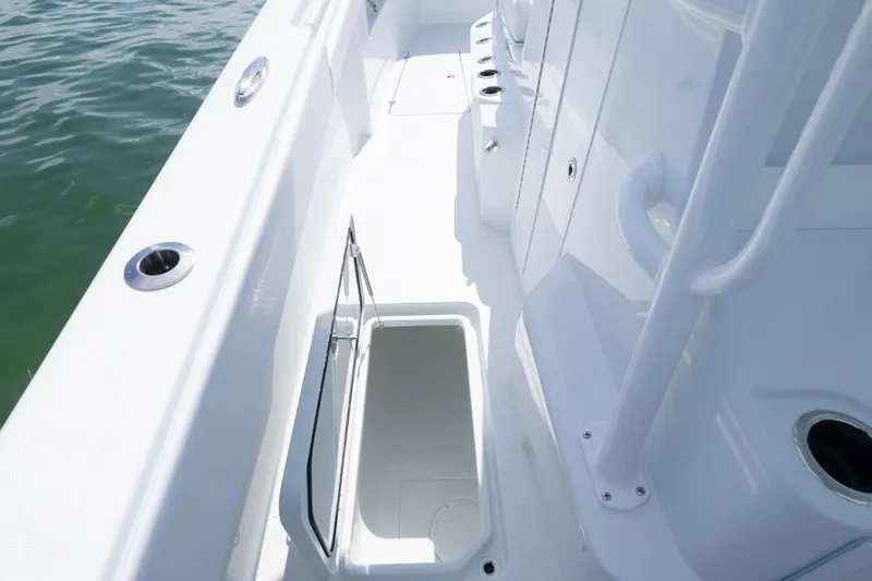 Slide: The Image of 2026 Invincible 33 Catamaran deck with open storage compartment, sleek design, and cup holders. - 23