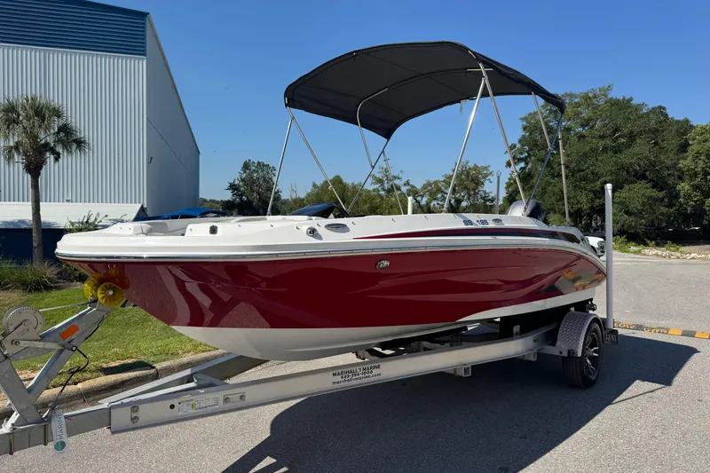 The Image of 2021 Hurricane SunDeck Sport 185 OB boat on trailer, red hull, black canopy, outdoor setting. - 0