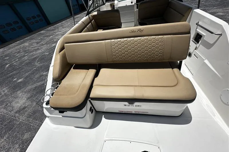 Slide: The Image of 2023 Sea Ray SDX 250 Outboard boat interior with beige seating and cup holders. - 11