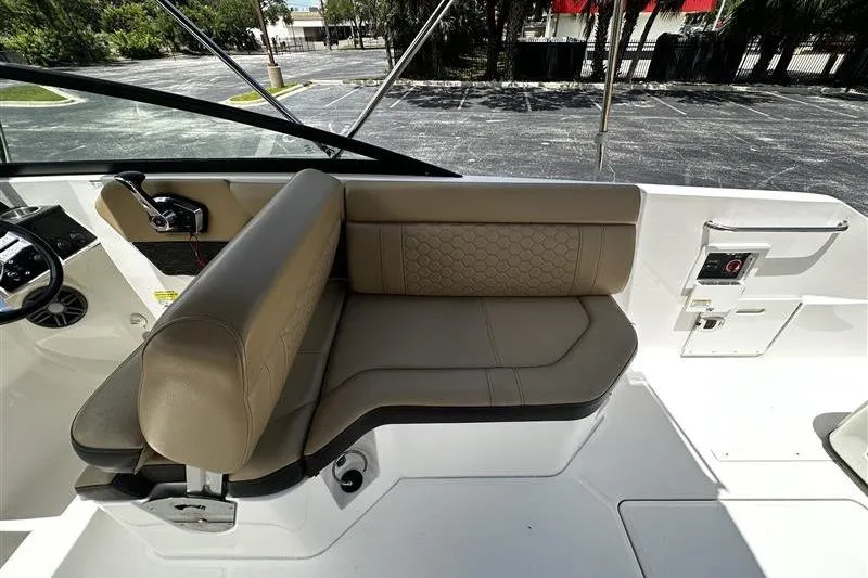 Slide: The Image of 2023 Sea Ray SDX 250 Outboard interior with beige seating and modern controls. - 9
