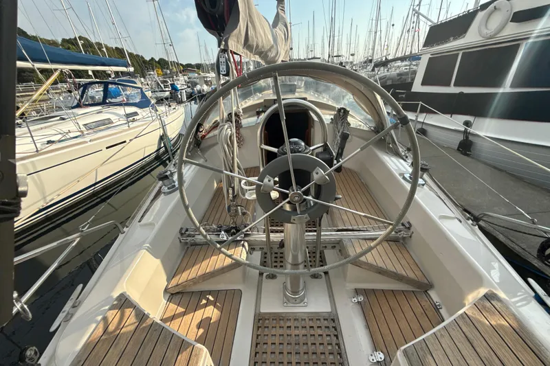 Slide: The Image of 1985 Dehler 372 sailboat cockpit with steering wheel, docked in a marina. - 11