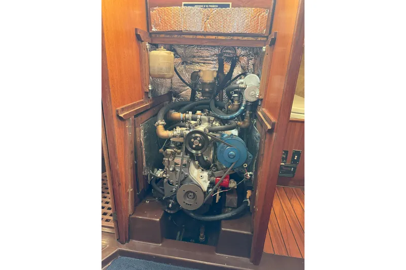 Slide: The Image of 1985 Dehler 372 engine compartment with visible components and wooden paneling. - 12