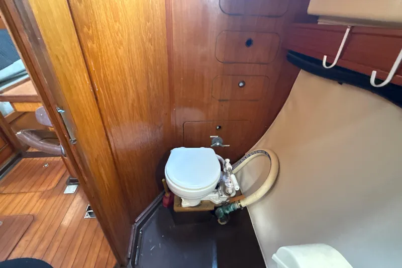 Slide: The Image of 1985 Dehler 372 yacht interior with wooden paneling and compact marine toilet. - 28