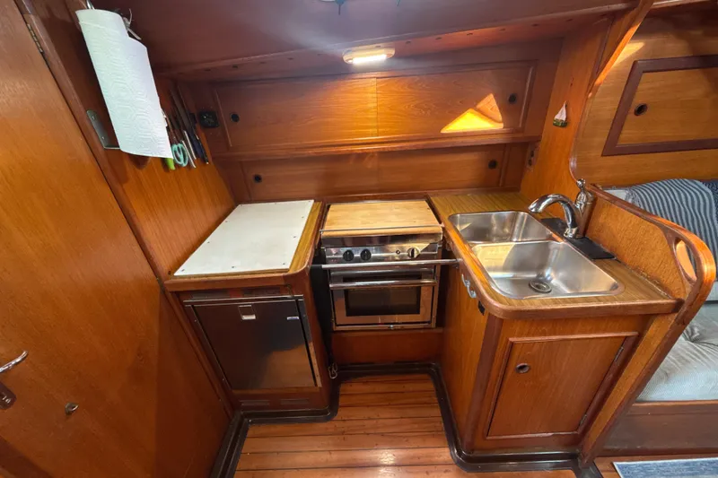 Slide: The Image of 1985 Dehler 372 yacht kitchen with wooden cabinetry, stove, sink, and compact design. - 7
