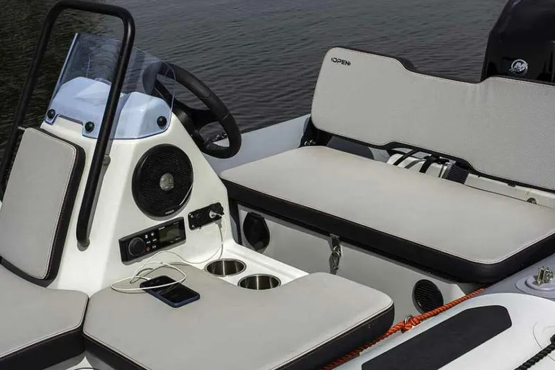 Slide: The Image of 2026 Zodiac Open 4.2 boat with steering console and outboard motor, parked outdoors. - 2