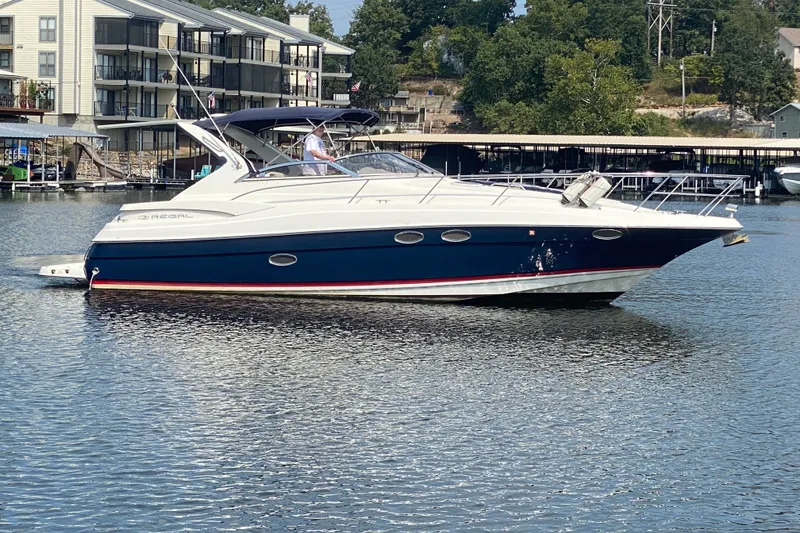 The Image of 2004 Regal Commodore 3560 yacht on a calm lake near waterfront buildings. - 1