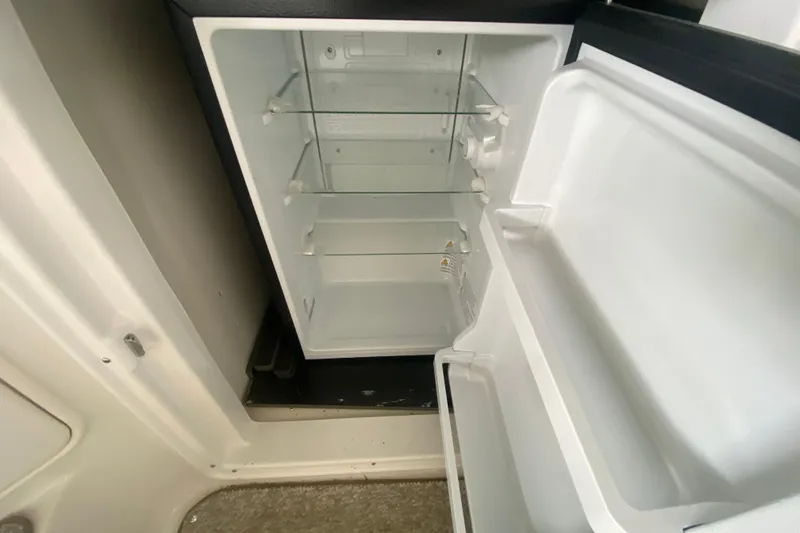 Slide: The Image of Open refrigerator inside 2004 Regal Commodore 3560 boat, featuring glass shelves and door storage. - 15