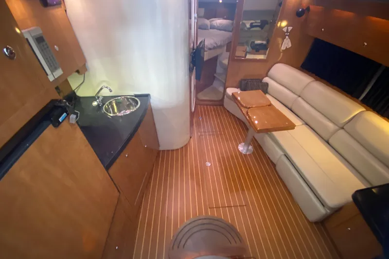 Slide: The Image of 2004 Regal Commodore 3560 yacht interior with kitchenette, seating area, and wood flooring. - 25