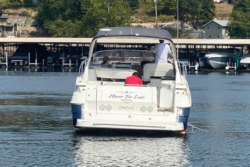 Slide: The Image of 2004 Regal Commodore 3560 boat on water near dock, people onboard, trees in background. - 4