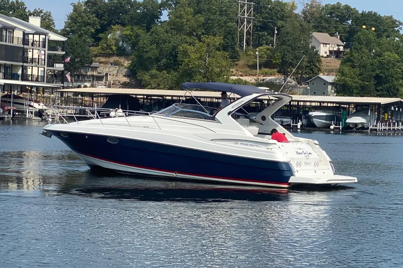 Slide: The Image of 2004 Regal Commodore 3560 boat docked on a serene lake with lush greenery. - 6