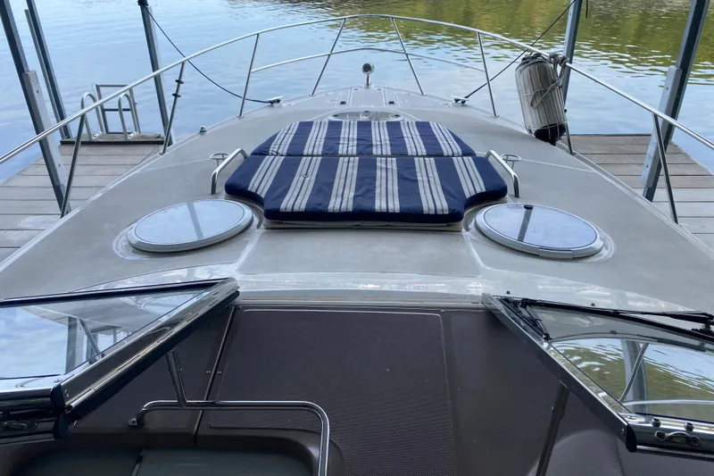Slide: The Image of 2004 Regal Commodore 3560 yacht deck with striped cushions, docked by calm water. - 9