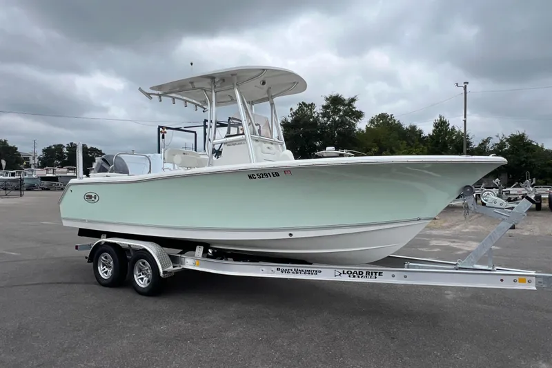 Slide: The Image of 2016 Sea Hunt Ultra 225 boat on trailer, parked outdoors under cloudy sky. - 2