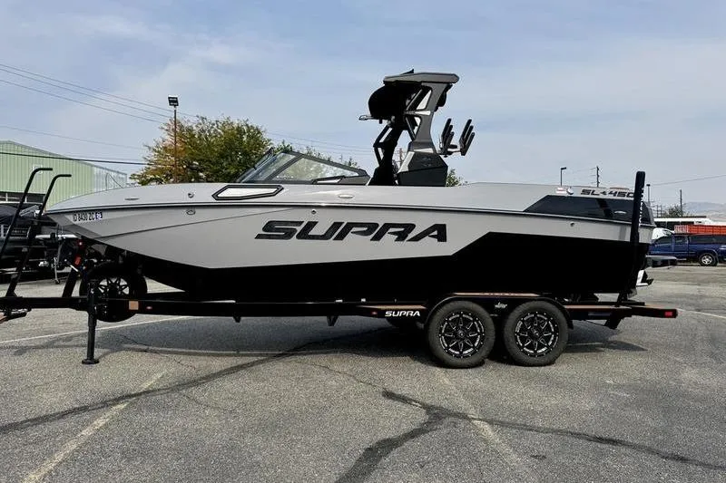 Slide: The Image of 2023 Supra SL boat on trailer, sleek design, parked outdoors. - 1