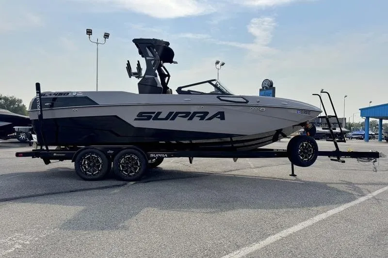 Slide: The Image of 2023 Supra SL boat on trailer in parking lot, side view. - 5