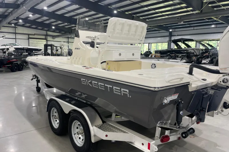 Slide: The Image of 2026 Skeeter SX221 boat in showroom, gray hull, dual-axle trailer, modern design. - 7