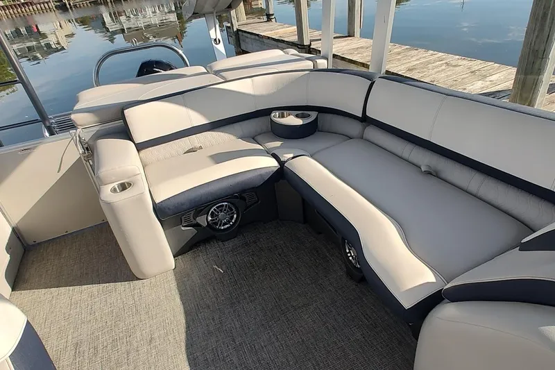 Slide: The Image of 2023 Tahoe Pontoon Cascade Funship interior with plush seating and cup holders by the dock. - 10