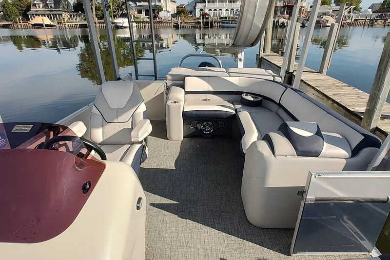 Slide: The Image of 2023 Tahoe Pontoon Cascade Funship interior with plush seating and helm, docked by calm waters. - 12